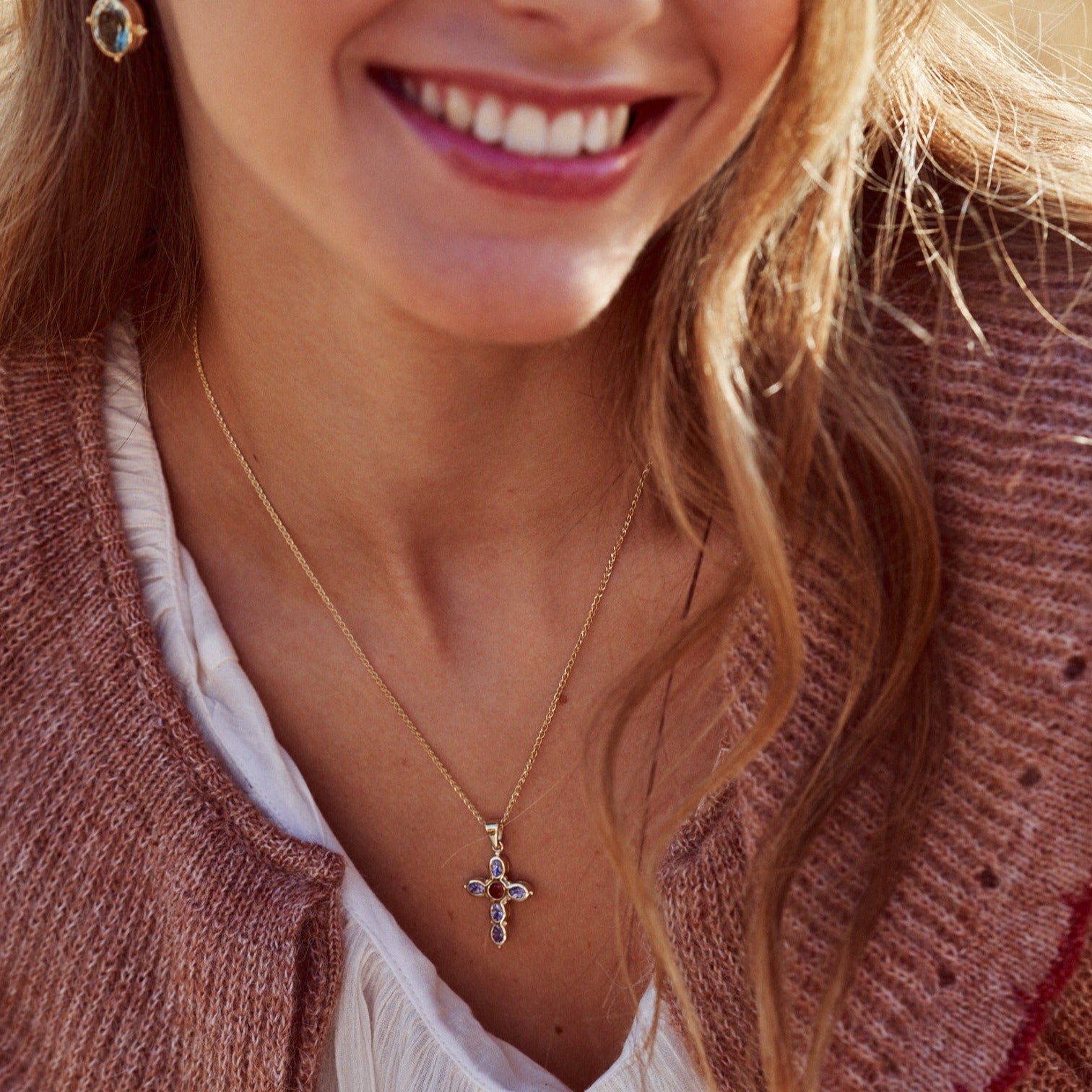 Mujer sonriente con el collar Cruz Martina, fabricado artesanalmente con oro de 9k.