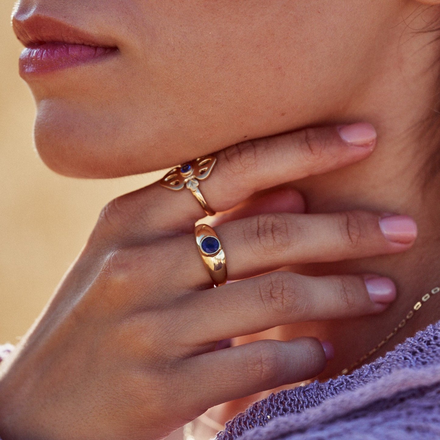 Mano de una mujer mostrando el anillo Simone, fabricado con oro de 18k y un zafiro azul natural en talla redonda.