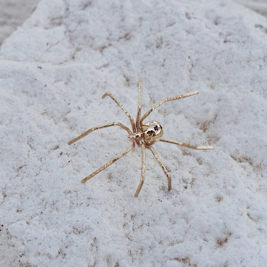 Detalle del Pin Spider, joya con forma de araña, fabricada en oro macizo de 9k con dos rubíes naturales.
